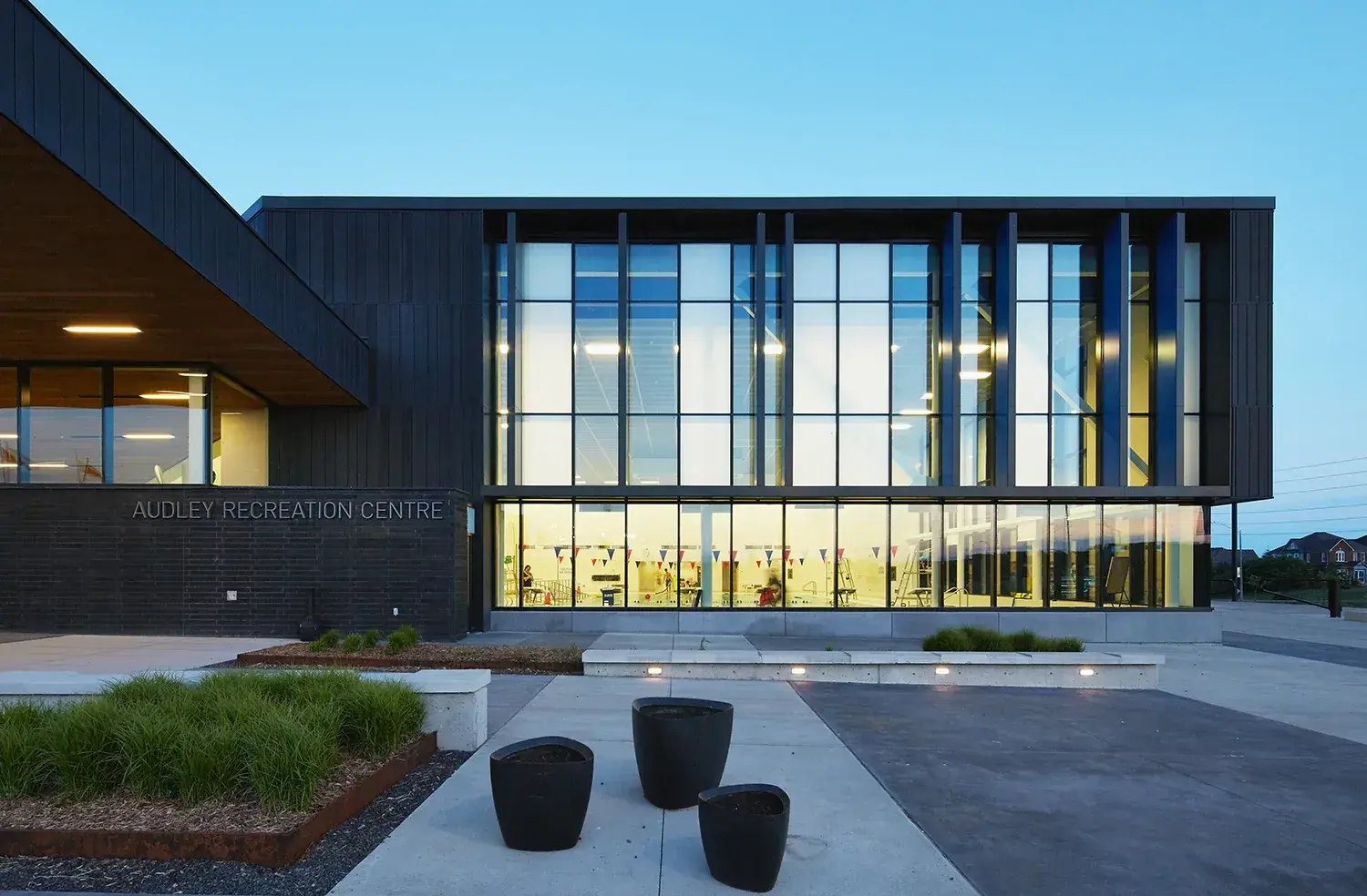 Dusk exterior of a SAWW Developments commercial project, glazed curtain wall lit from within
